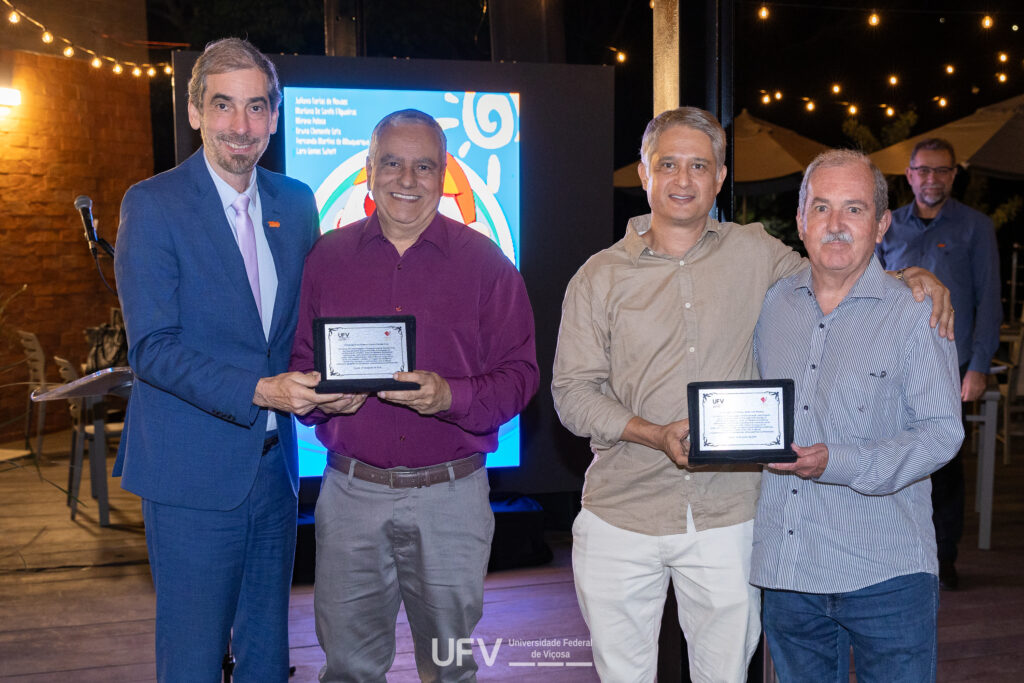 Reitor da UFV, professor Demetrius David da Silva, entrega placa ao professor Cosme Damião Cruz, enquanto o presidente da Funarbe, professor Rodrigo Gava, homenageia Adair José Regazzi - ambos pela publicação de Modelos Biométricos Aplicados ao Melhoramento Genético