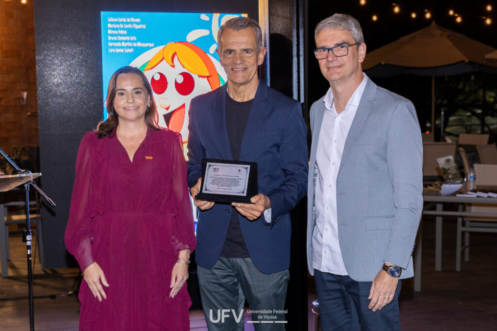 Vice-reitora da UFV, professora Rejane Nascentes, com diretor da Editora UFV, professor Bricio dos Santos Reis (à direita na foto), entregando placa em homangem ao  professor Aluizio Borém, autor de Melhoramento de Plantas, entre outras